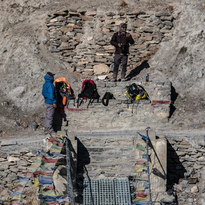 Trekkers resting at a suspension Bridge on the trail to the Annapurna Circuit trek in Nepal