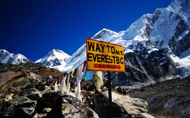 Sign post on the trail to Everest Base Camp with Mountain peak visible in the Khumbu region of Nepal