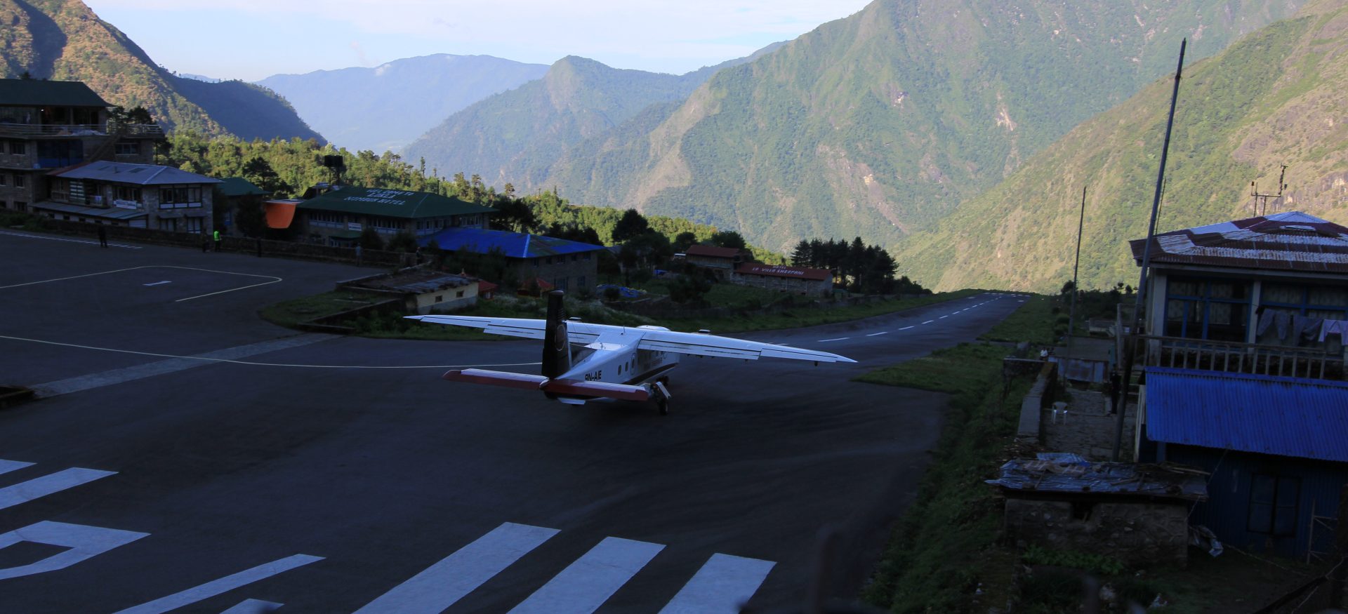 Tenzing Hillary Airport at Lukla Nepal with small Twin Otter aircraft on the runway and mountain backdrop