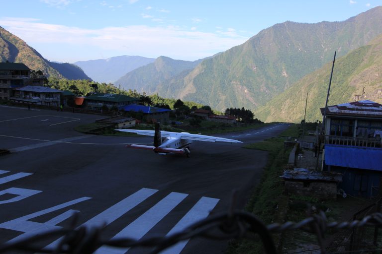 Tenzing Hillary Airport at Lukla Nepal with small Twin Otter aircraft on the runway and mountain backdrop