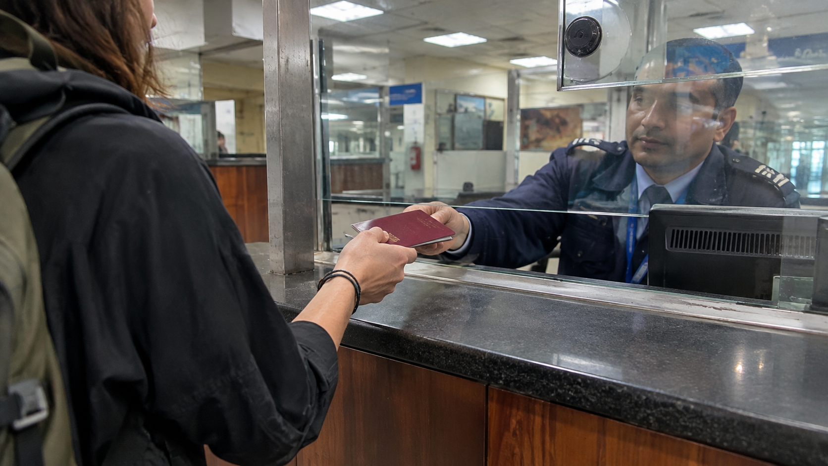 Traveler handing a passport to an immigration officer at a visa counter in Nepal